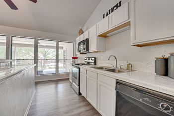 A kitchen with white cabinets and a black dishwasher.